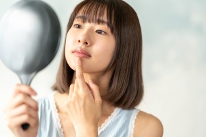 鏡で口元をチェックする女性